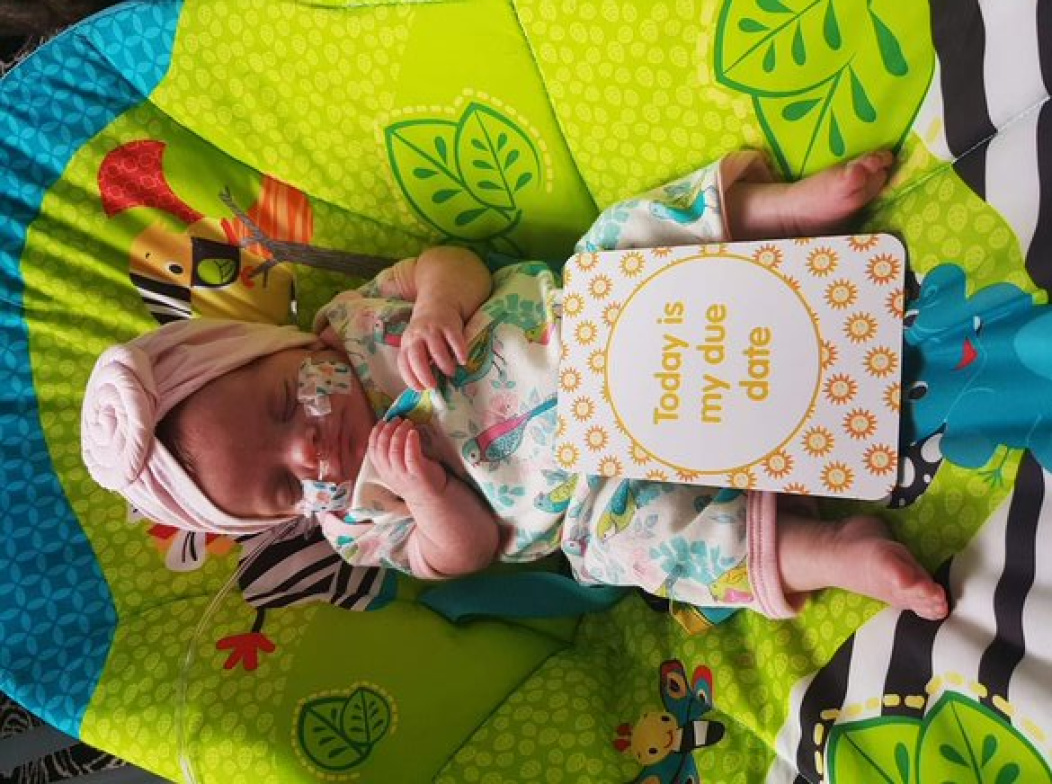 premature baby with milestone card