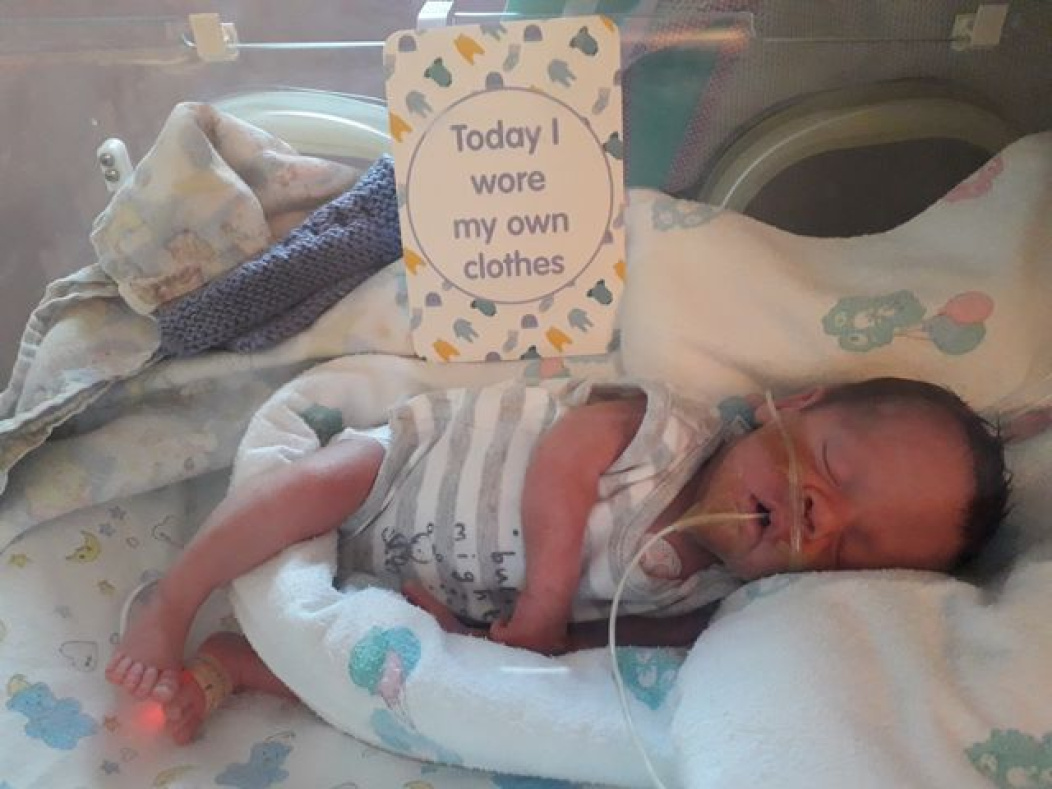 Preemie baby with milestone card