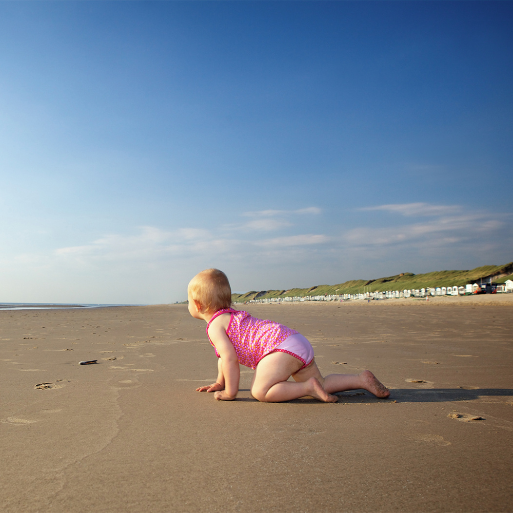 A baby crawling on a beach
