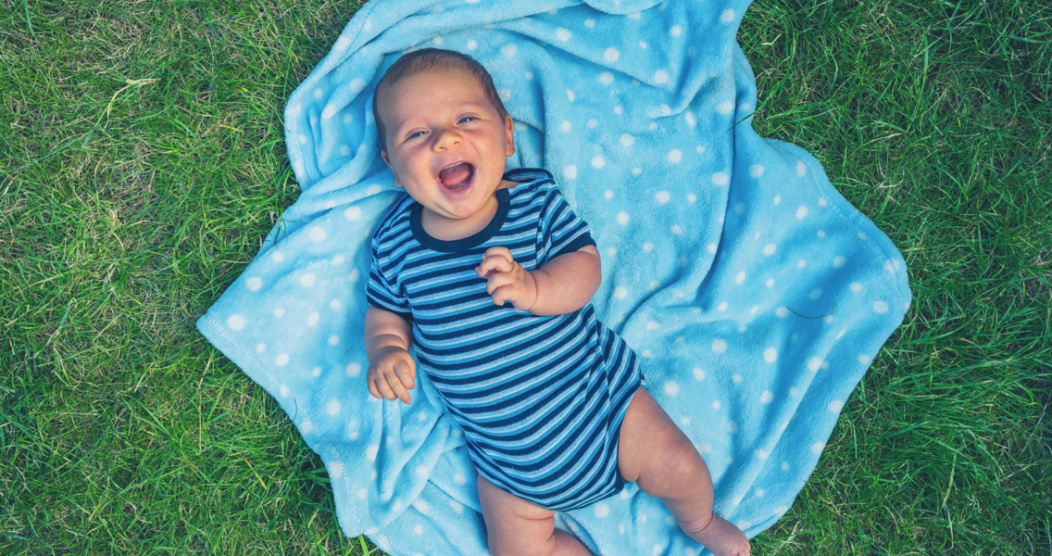 A baby lying on a picnic blanket