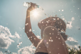 A woman splashing water over her to cool down