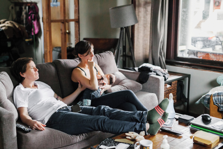 a couple relaxing on a couch while breastfeeding a baby