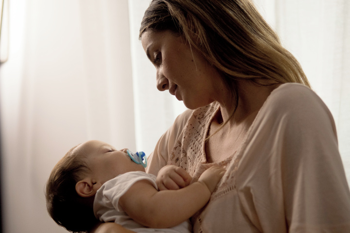 Madre junto a su bebé dormido.