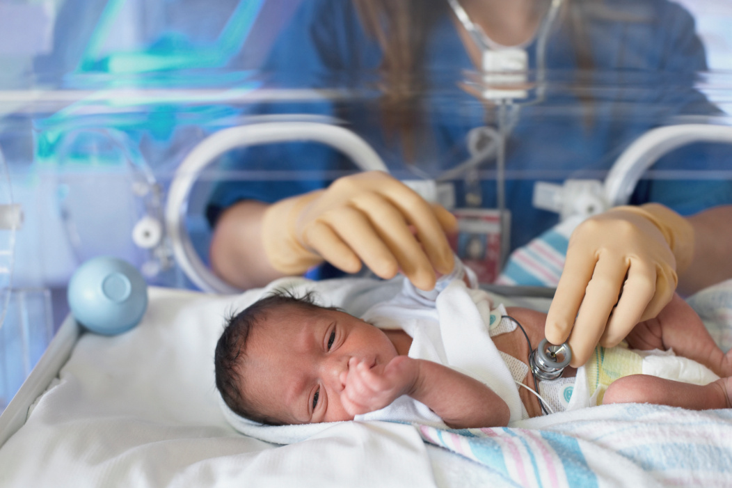 baby in incubator with nurse