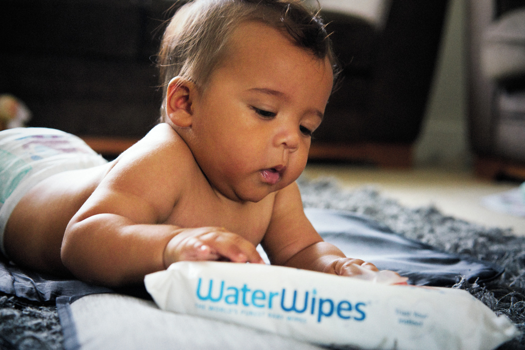 a baby playing with a packet of WaterWipes Baby Wipes Original
