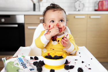A toddler eating food with its hands