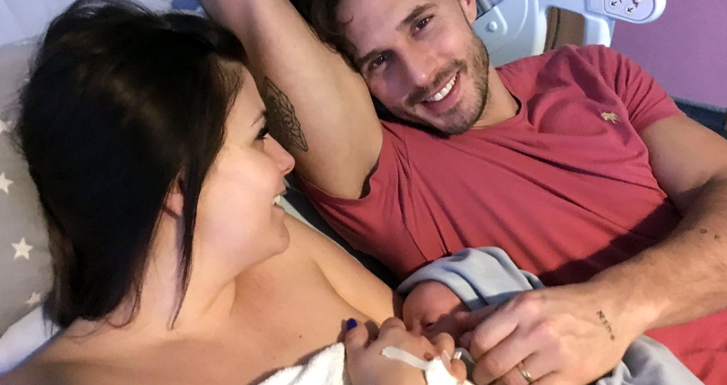 Una pareja acostada en una cama amamantando a su bebé recién nacido
