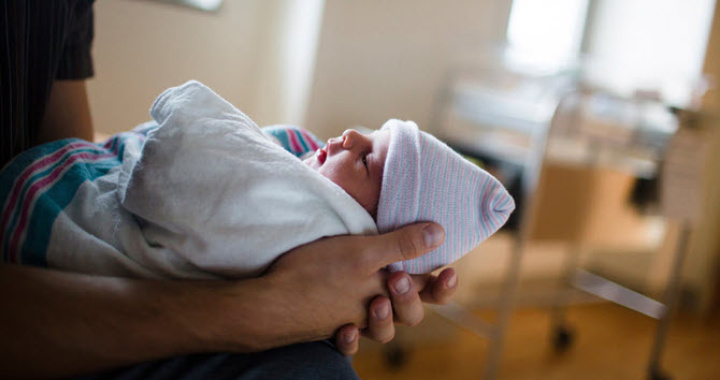 newborn held by its father