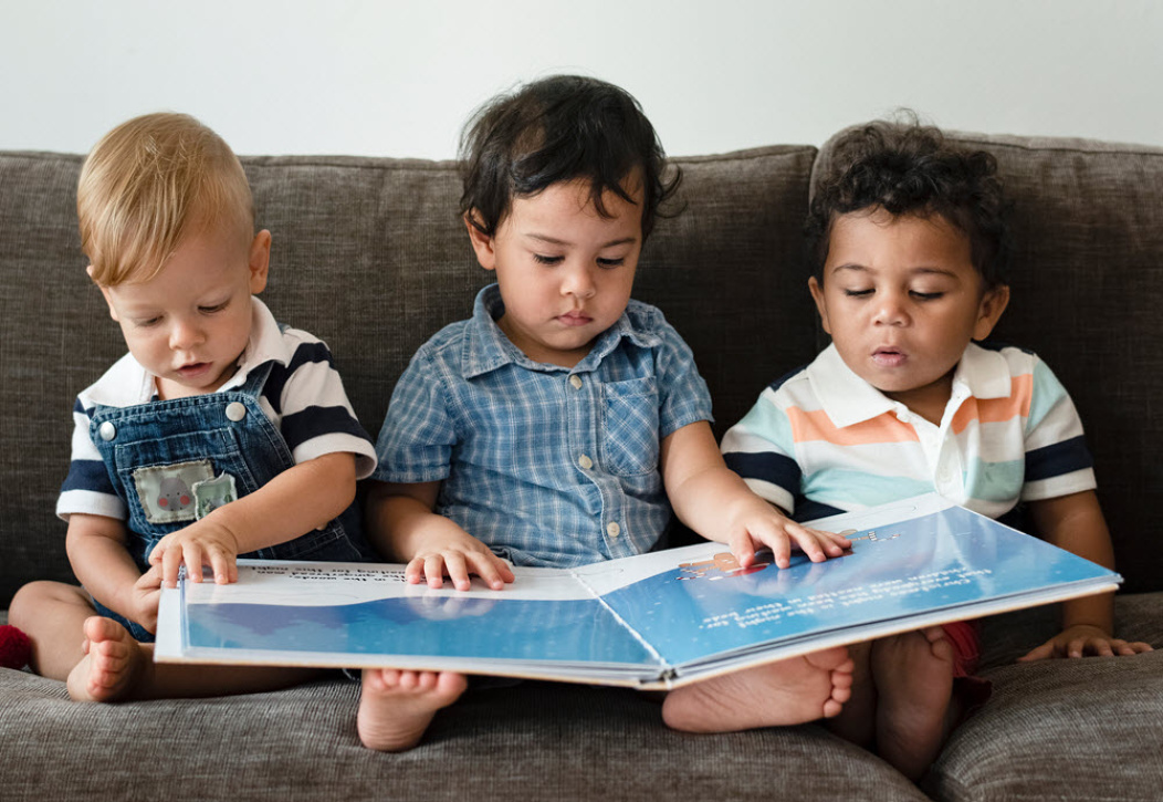 tres niños leyendo un libro.