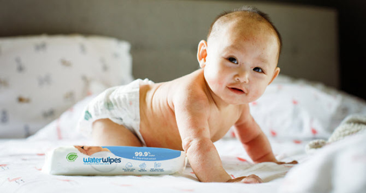 A newborn baby crawling on a mat