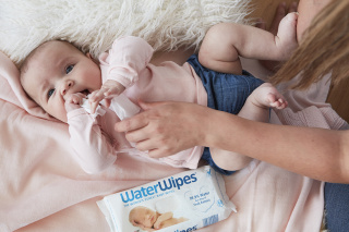 a baby with a WaterWipes pack