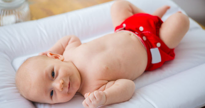 A baby lying on a nappy changing table