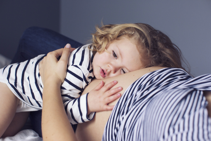 child laying on pregnant woman's belly