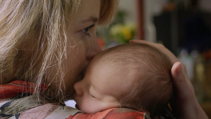 A mother kissing her newborn baby.