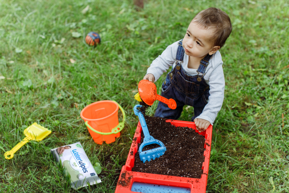 A toddler playing on grass with his toys