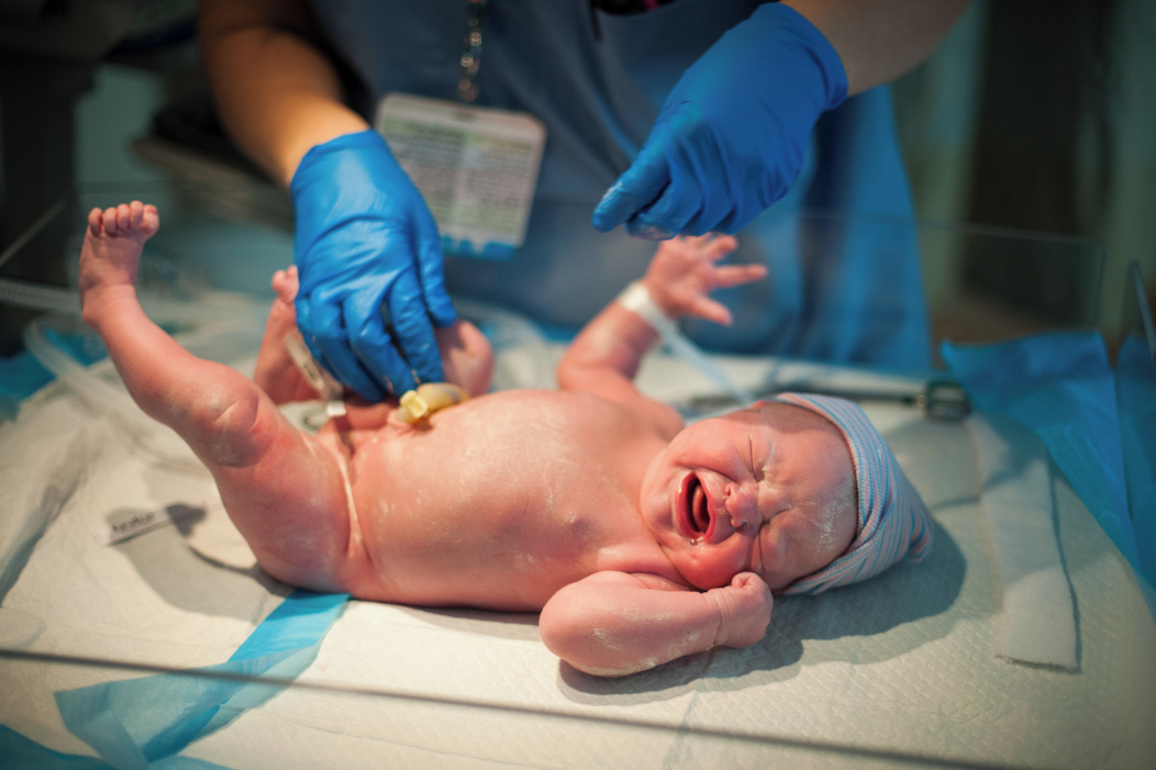 A healthcare professional tending to a baby in an incubator.